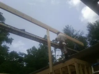 Carpenter setting a ridge beam over a new addition frame — Ice Dam Removal by Roofing Brothers in Lodi